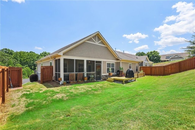 rear view of house featuring a lawn, fence, and a sunroom