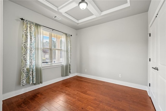 empty room featuring visible vents, baseboards, beamed ceiling, wood finished floors, and coffered ceiling