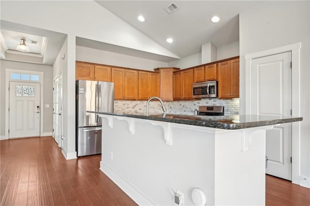 kitchen with stainless steel appliances, brown cabinets, a breakfast bar, and dark wood-style flooring