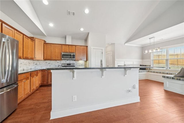 kitchen with a kitchen breakfast bar, stainless steel appliances, and vaulted ceiling