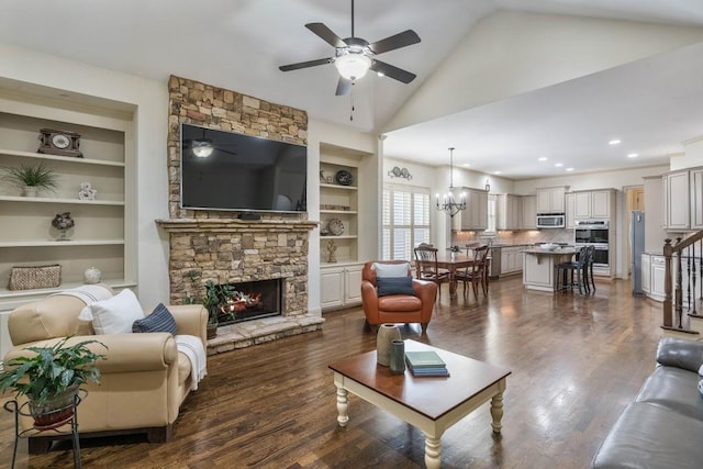 living room featuring a stone fireplace, built in features, ceiling fan with notable chandelier, and dark hardwood / wood-style flooring