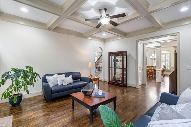 living room with dark hardwood / wood-style floors, beamed ceiling, ceiling fan with notable chandelier, crown molding, and coffered ceiling