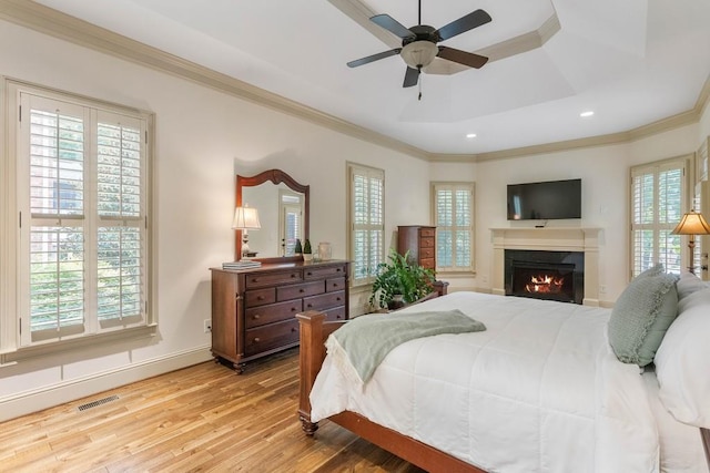 bedroom featuring a raised ceiling, light hardwood / wood-style flooring, crown molding, and ceiling fan