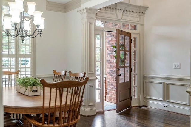 dining room with dark wood-type flooring, crown molding, a chandelier, and ornate columns