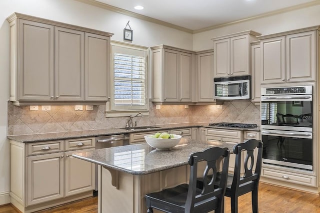 kitchen featuring ornamental molding, sink, a center island, appliances with stainless steel finishes, and light stone counters