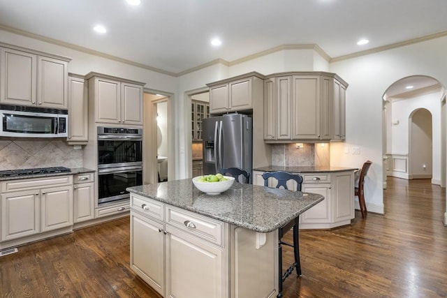 kitchen with a kitchen island, a kitchen bar, stainless steel appliances, and dark hardwood / wood-style flooring