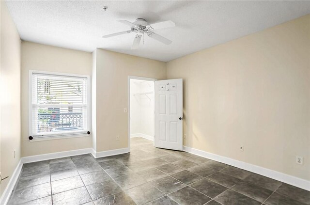 empty room with baseboards, a textured ceiling, and ceiling fan