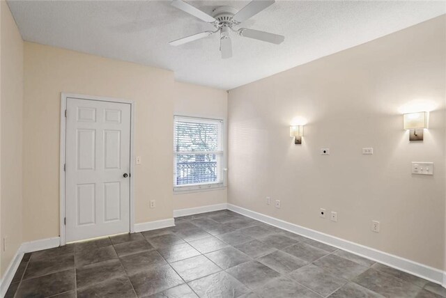 spare room with a textured ceiling, baseboards, and a ceiling fan