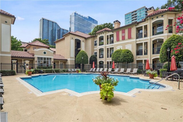 community pool with a patio area and fence