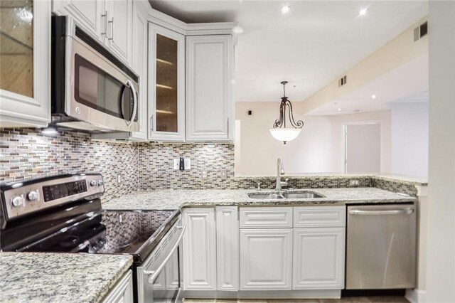 kitchen with decorative backsplash, appliances with stainless steel finishes, white cabinetry, and a sink
