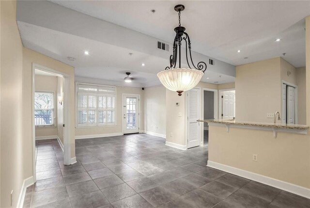kitchen with a breakfast bar area, recessed lighting, baseboards, and light stone countertops