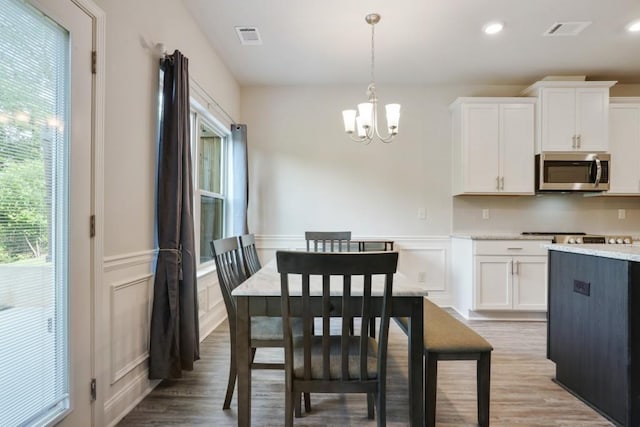 1360 Sugar Glen Ct, Lawrenceville, GA 30044 - dining space with a decorative wall, plenty of natural light, a chandelier, wood finished floors, and a wainscoted wall
