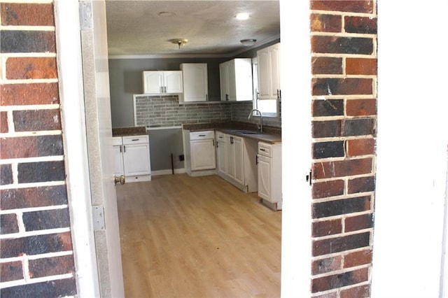 1189 Hartley St, Macon, GA 31206 - kitchen featuring a sink, white cabinets, dark countertops, light wood-type flooring, and backsplash