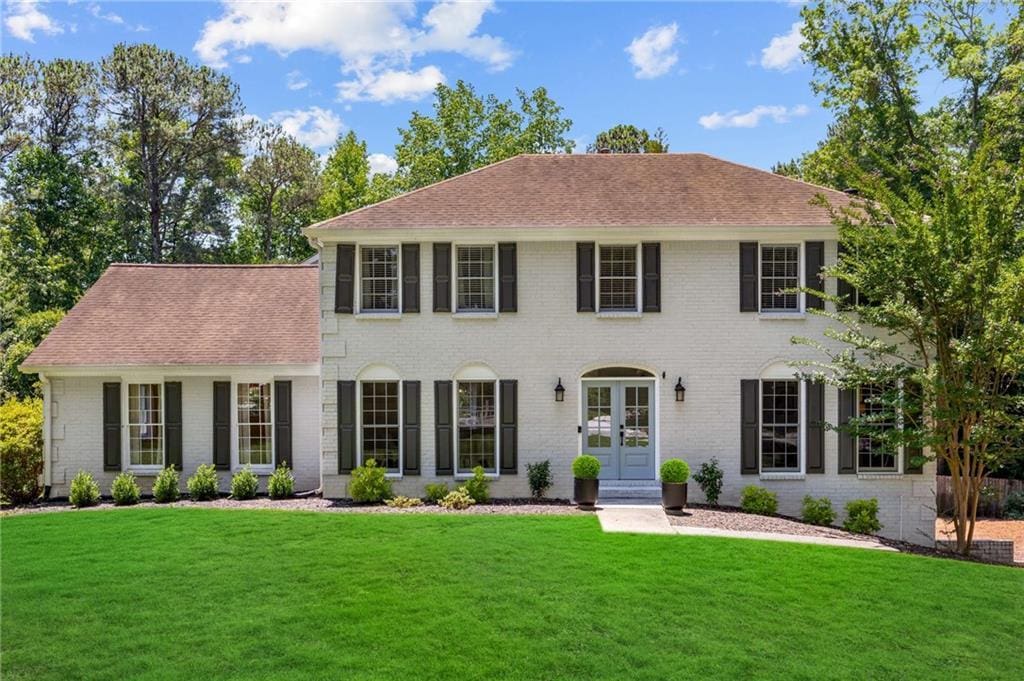 colonial inspired home featuring a front lawn and french doors