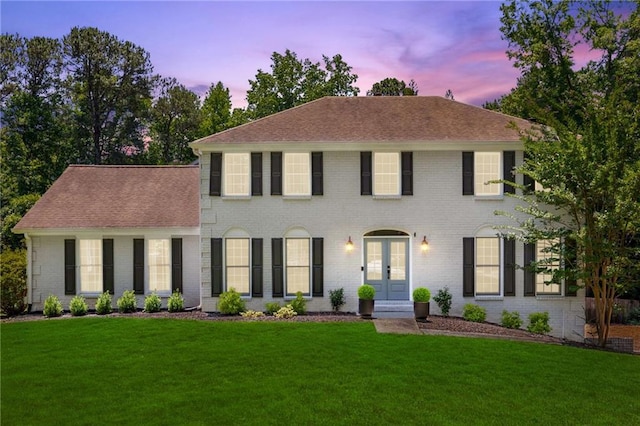 colonial-style house featuring french doors and a lawn