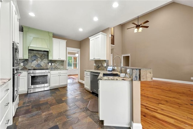 kitchen with white cabinets, sink, kitchen peninsula, stainless steel appliances, and light stone countertops