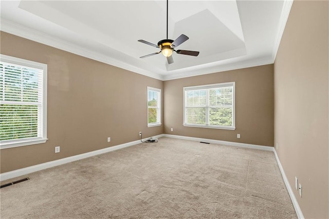 carpeted empty room with crown molding, a tray ceiling, and ceiling fan