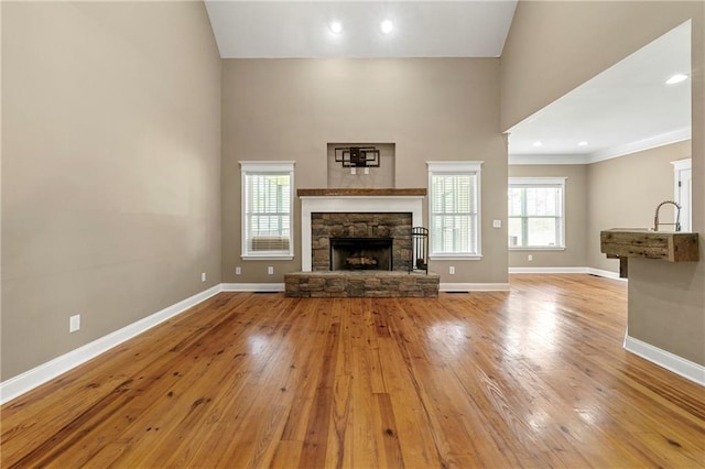 unfurnished living room featuring ornamental molding, light hardwood / wood-style floors, a fireplace, and high vaulted ceiling