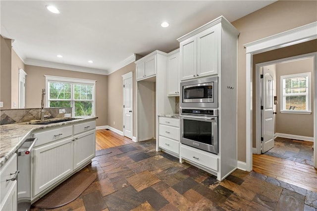 kitchen featuring sink, white cabinetry, stainless steel appliances, crown molding, and light stone countertops