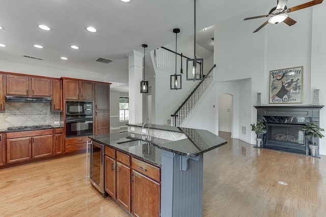 7405 Brookstone Way, Flowery Branch, GA 30542 - kitchen with black appliances, beverage cooler, ceiling fan, dark stone counters, and under cabinet range hood