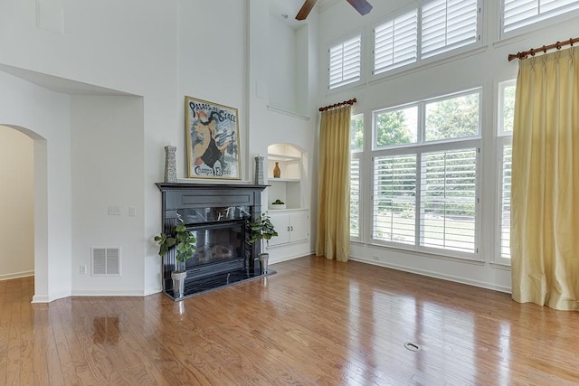 7405 Brookstone Way, Flowery Branch, GA 30542 - living room featuring ceiling fan, arched walkways, a towering ceiling, wood finished floors, and a high end fireplace