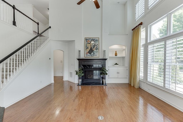 7405 Brookstone Way, Flowery Branch, GA 30542 - living room with a high ceiling, a ceiling fan, arched walkways, stairway, and a fireplace