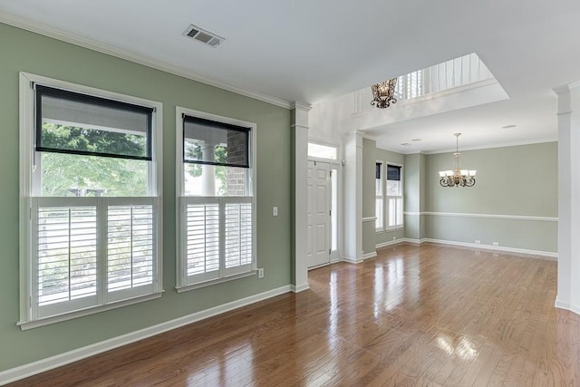 7405 Brookstone Way, Flowery Branch, GA 30542 - empty room with a chandelier, plenty of natural light, crown molding, wood finished floors, and decorative columns
