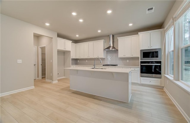 251 Arnewood Cir, Mcdonough, GA 30253 - kitchen featuring appliances with stainless steel finishes, wall chimney exhaust hood, light wood-style flooring, light countertops, and recessed lighting