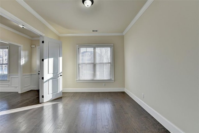 spare room with ornamental molding, a healthy amount of sunlight, and dark wood-type flooring