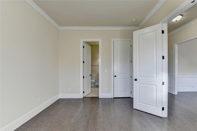 unfurnished bedroom featuring ornamental molding, dark wood-type flooring, and connected bathroom