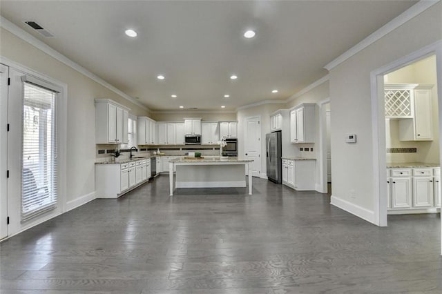 kitchen featuring appliances with stainless steel finishes, white cabinetry, sink, dark hardwood / wood-style flooring, and a center island