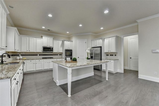 kitchen with light stone counters, sink, stainless steel appliances, and a center island