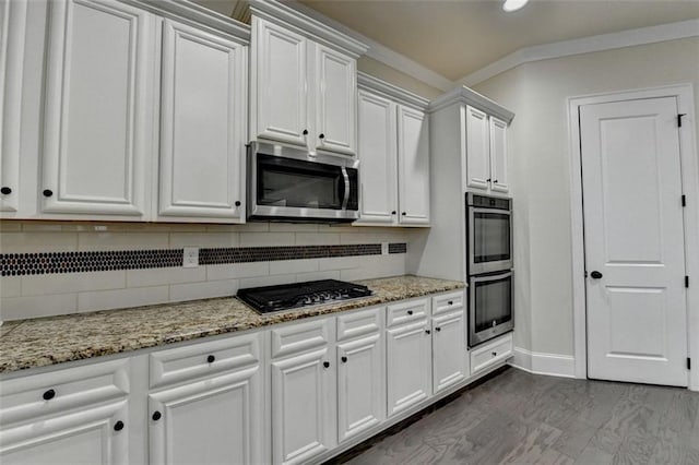 kitchen with white cabinetry, light stone counters, tasteful backsplash, and appliances with stainless steel finishes