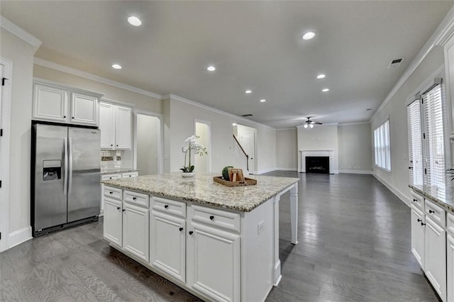 kitchen with stainless steel fridge with ice dispenser, crown molding, white cabinets, and a kitchen island