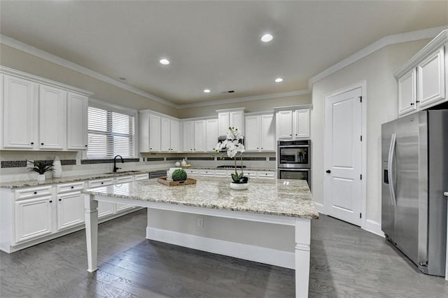 kitchen featuring stainless steel appliances, a center island, white cabinets, and light stone counters