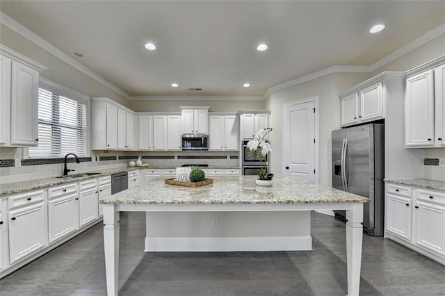 kitchen featuring light stone counters, sink, stainless steel appliances, and a kitchen island