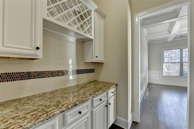 kitchen featuring beamed ceiling, white cabinetry, coffered ceiling, light stone counters, and dark wood-type flooring