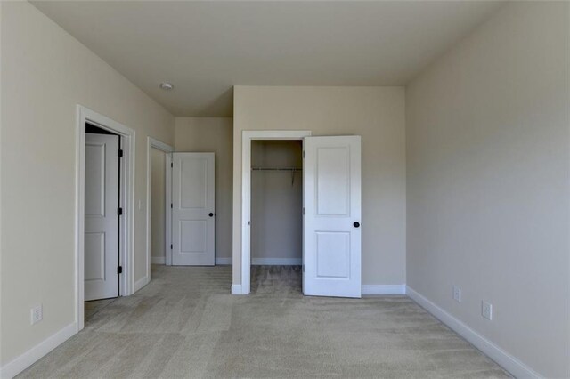 unfurnished bedroom with light colored carpet and a closet