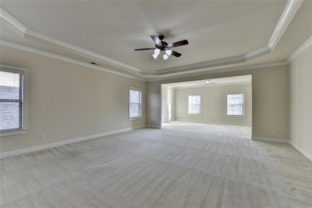 spare room featuring crown molding, a tray ceiling, and light carpet