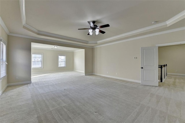 carpeted empty room featuring a raised ceiling, ornamental molding, and ceiling fan