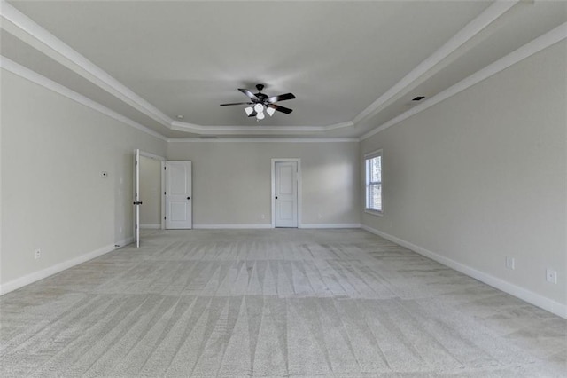 spare room featuring light carpet, a tray ceiling, ornamental molding, and ceiling fan