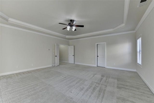 unfurnished room featuring ornamental molding, light carpet, ceiling fan, and a tray ceiling