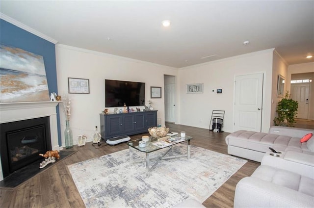 living room with ornamental molding, a glass covered fireplace, and wood finished floors