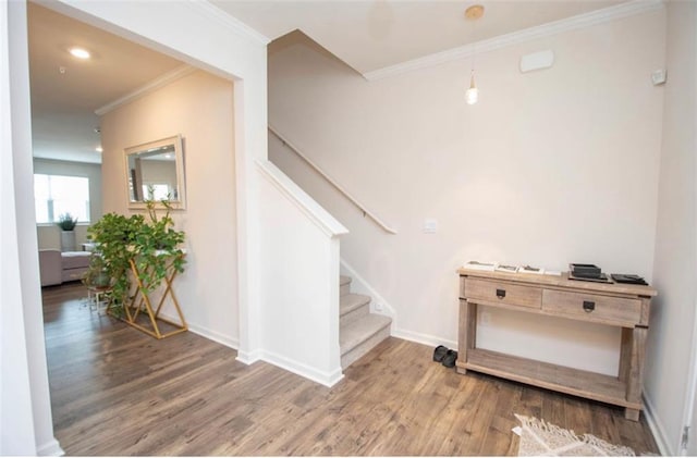 staircase featuring crown molding, baseboards, and wood finished floors