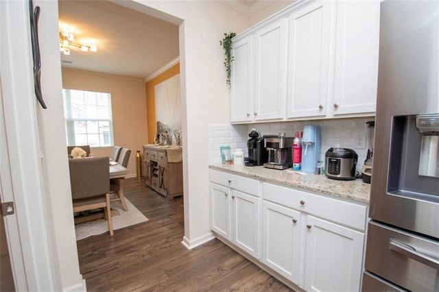 kitchen with decorative backsplash, dark wood finished floors, stainless steel fridge, ornamental molding, and white cabinetry