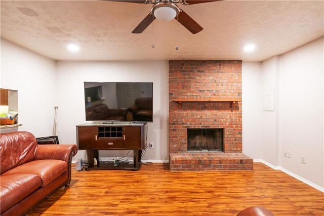 1406 Springleaf Cir SE, Smyrna, GA 30080 - living area with wood finished floors, a textured ceiling, a ceiling fan, baseboards, and a brick fireplace
