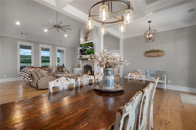 dining area with ceiling fan with notable chandelier, high vaulted ceiling, ornamental molding, beam ceiling, and light hardwood / wood-style flooring