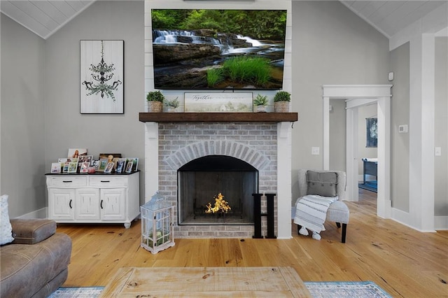 sitting room featuring lofted ceiling, a brick fireplace, and light hardwood / wood-style flooring