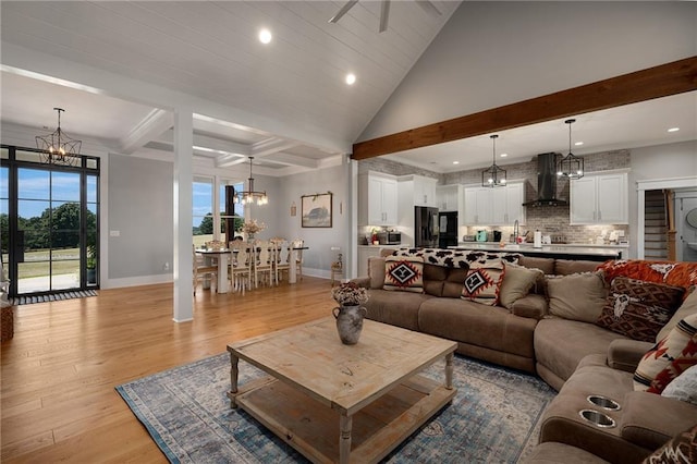 living room featuring beamed ceiling, plenty of natural light, light hardwood / wood-style floors, and a notable chandelier