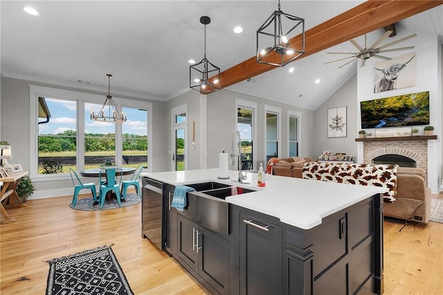 kitchen with hanging light fixtures, stainless steel dishwasher, sink, and a center island with sink